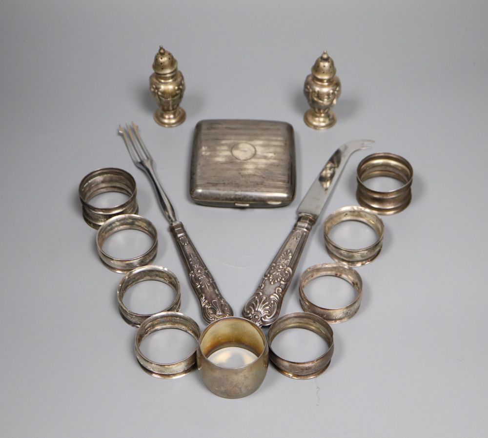 Nine assorted silver napkin rings, a pair of silver pepperettes, a silver cigarette case and pair of silver handled servers.